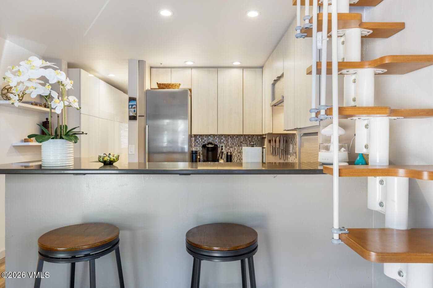Kitchen counter with bar stools and stairs to loft