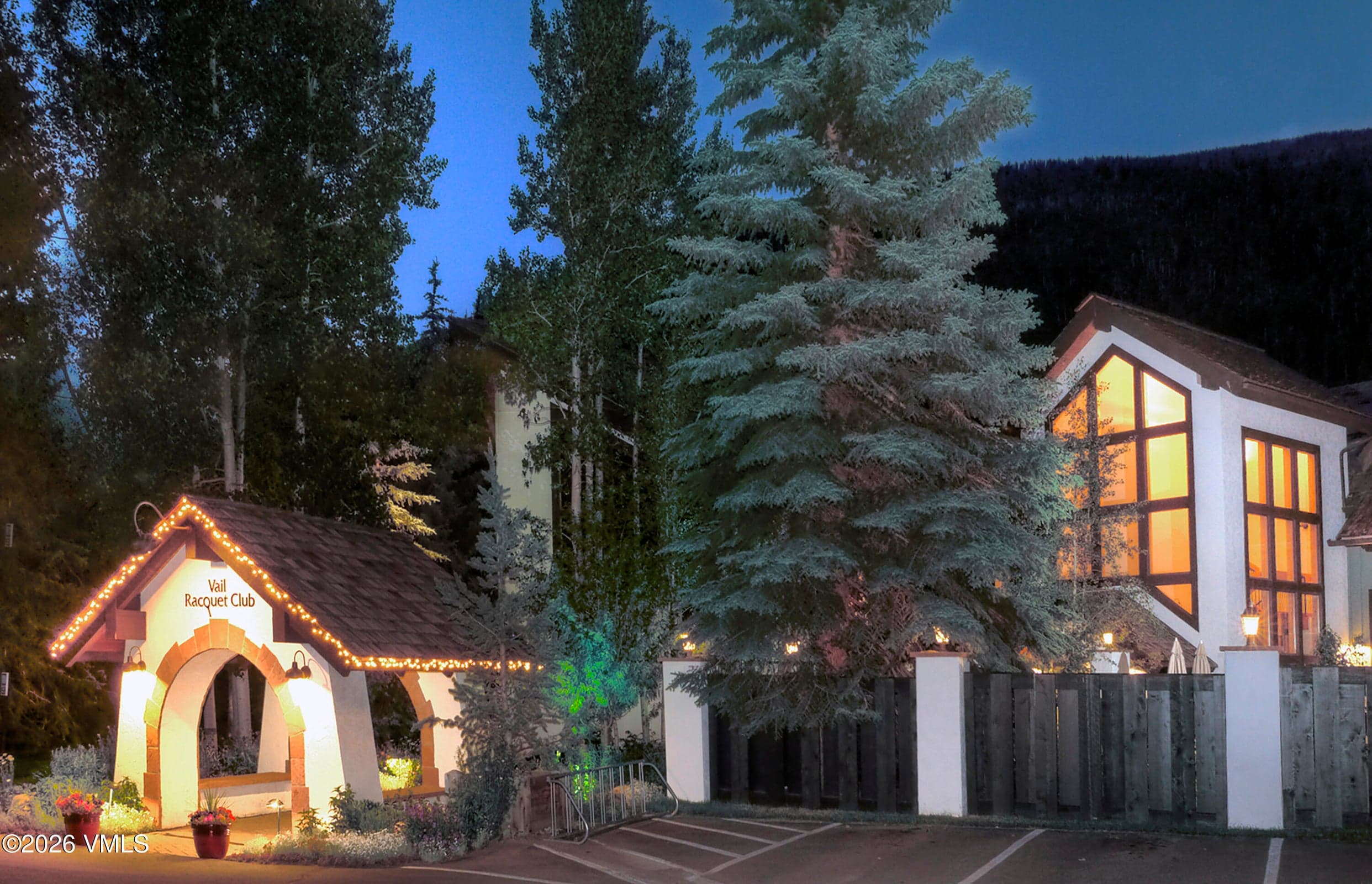 Twilight view of the iconic Vail Racquet Club entrance sign, lit archway and mountain backdrop.