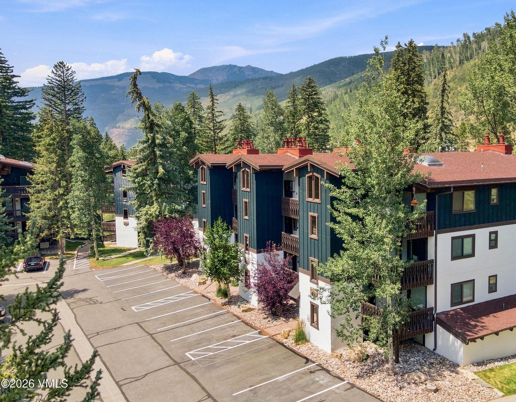 Building 7 exterior with mature aspens and mountain views beyond.