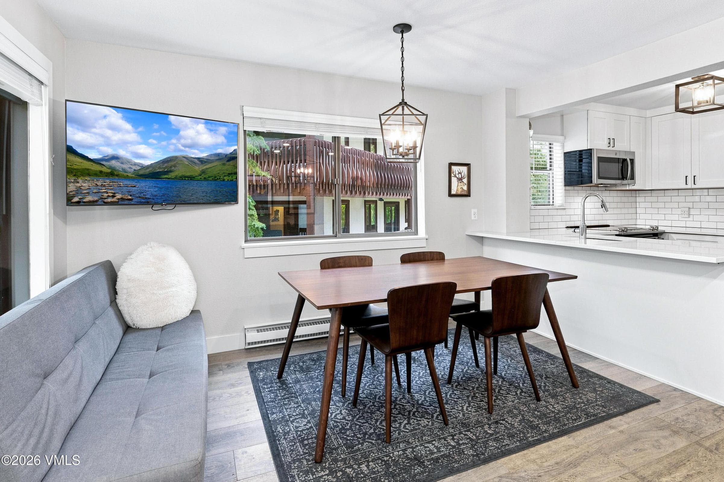 Dining area with wood table, wall-mounted TV, and mountain view window.