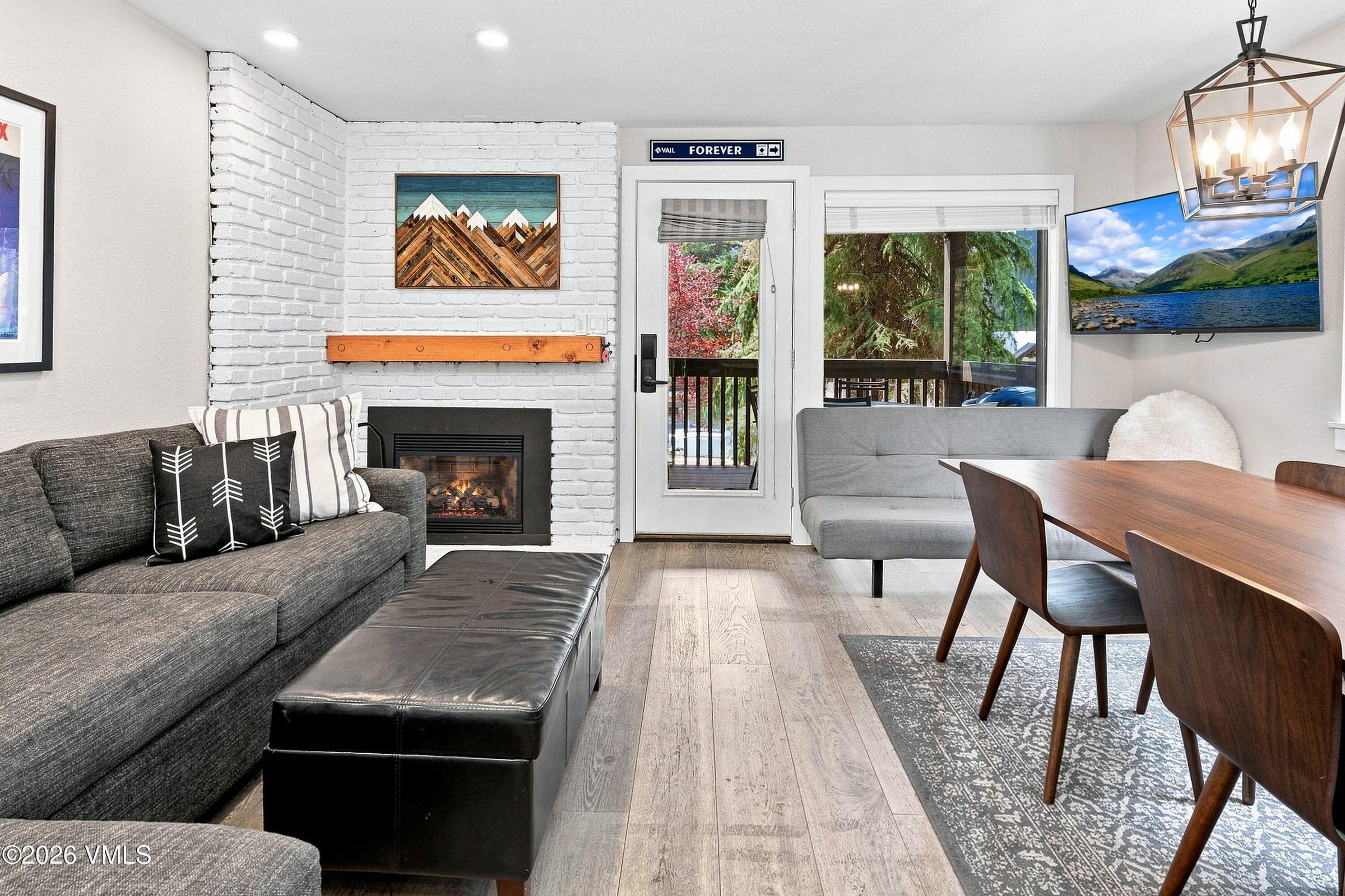 Open living and dining area with fireplace, deck access, and wall-mounted TV.