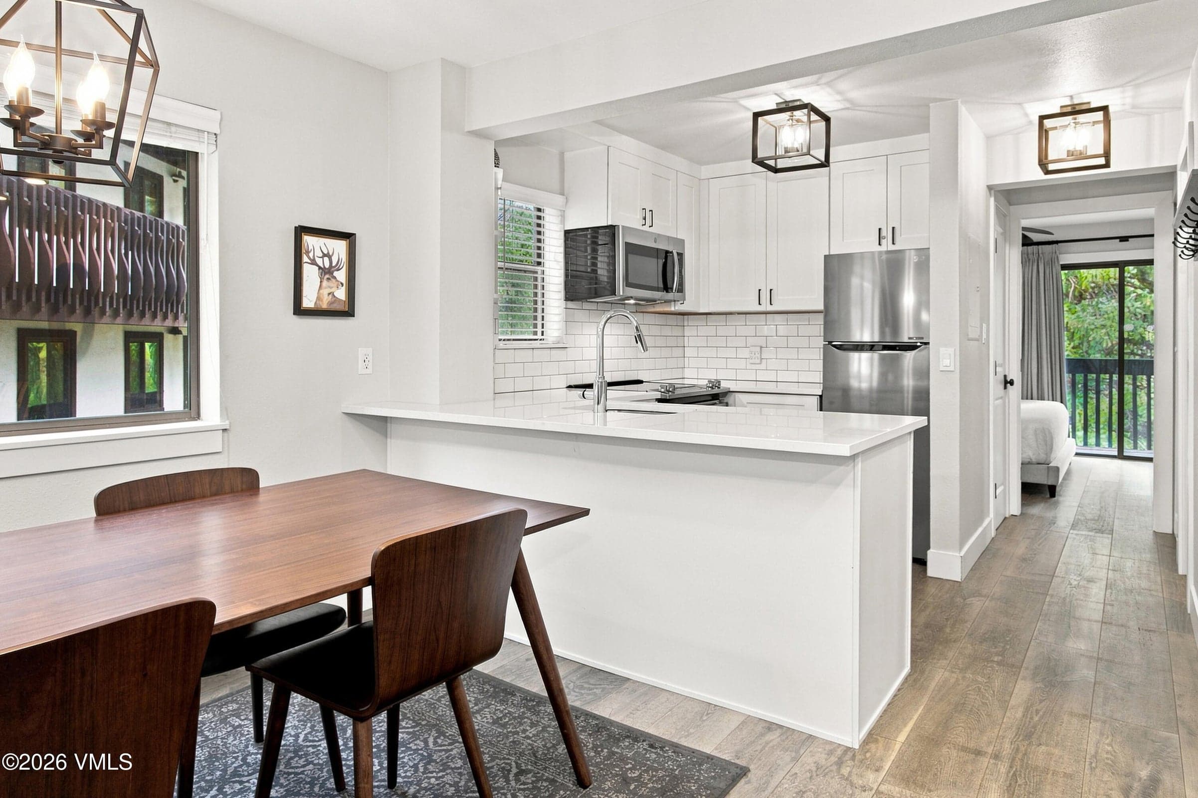 Kitchen pass-through with peninsula seating and view toward primary bedroom.