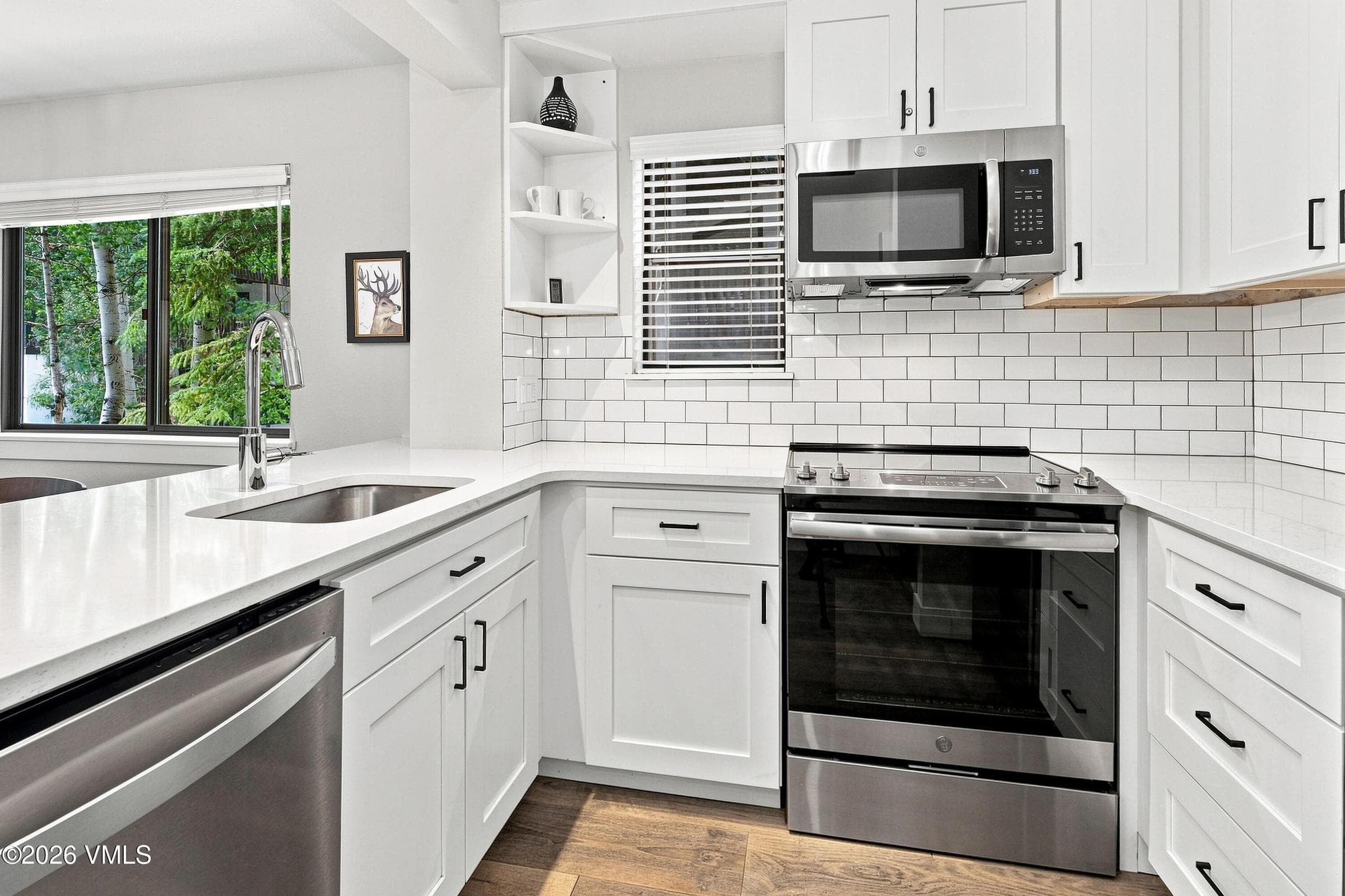 Kitchen detail: stainless range, microwave, and white shaker cabinetry.