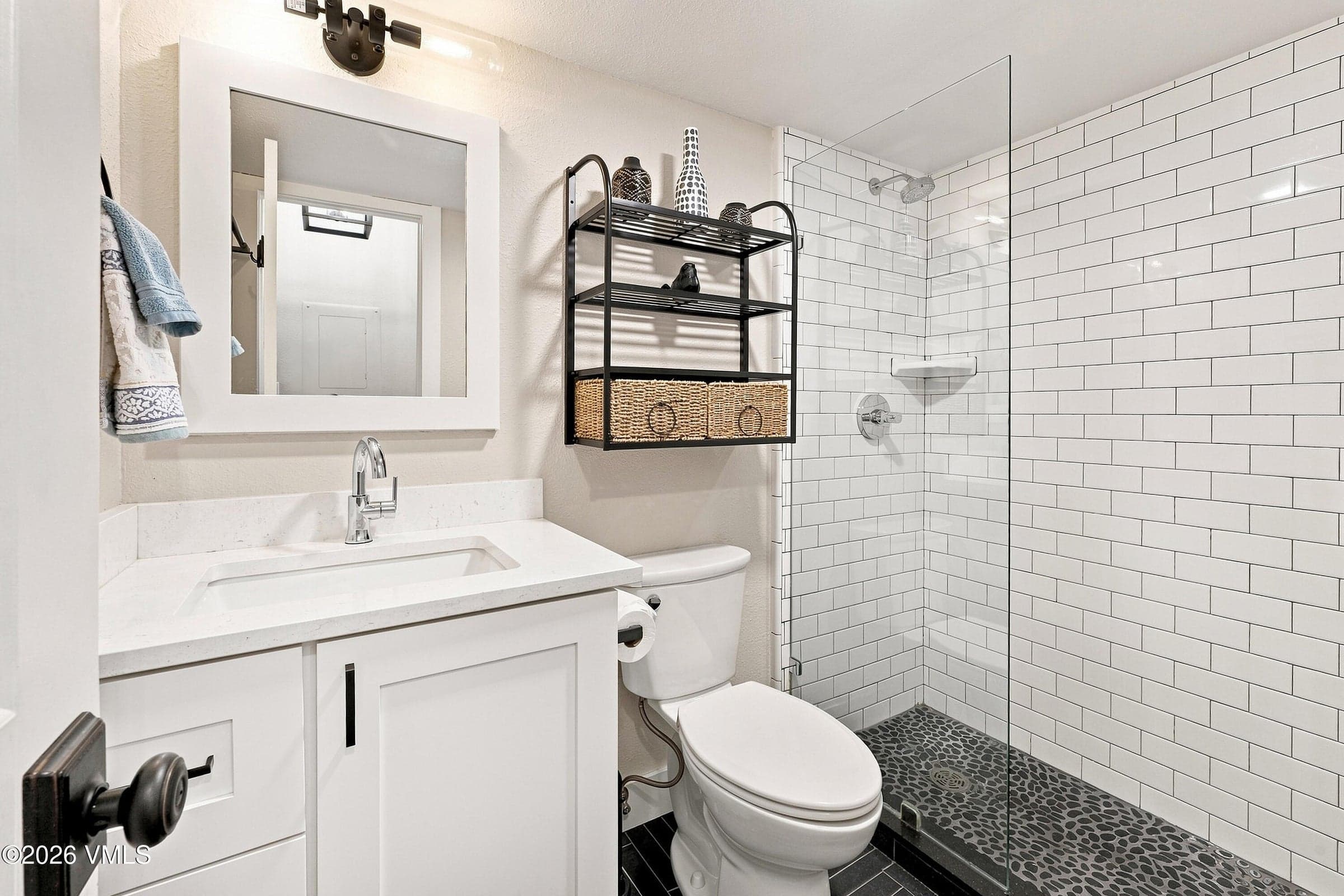 Bath with walk-in glass shower and subway tile surround.