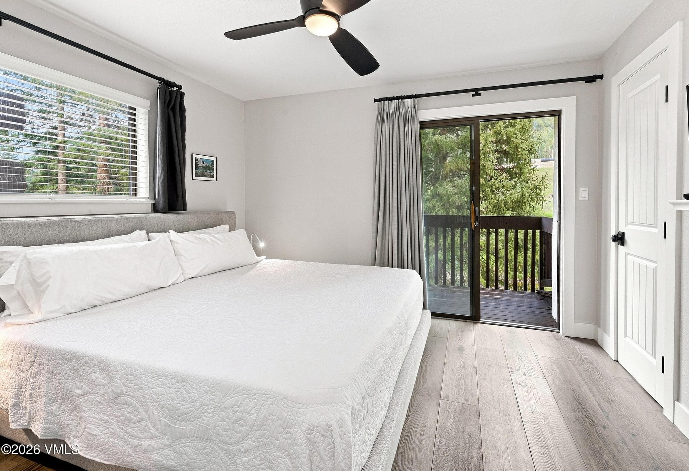 Primary bedroom with king bed, ceiling fan, and slider to private balcony.
