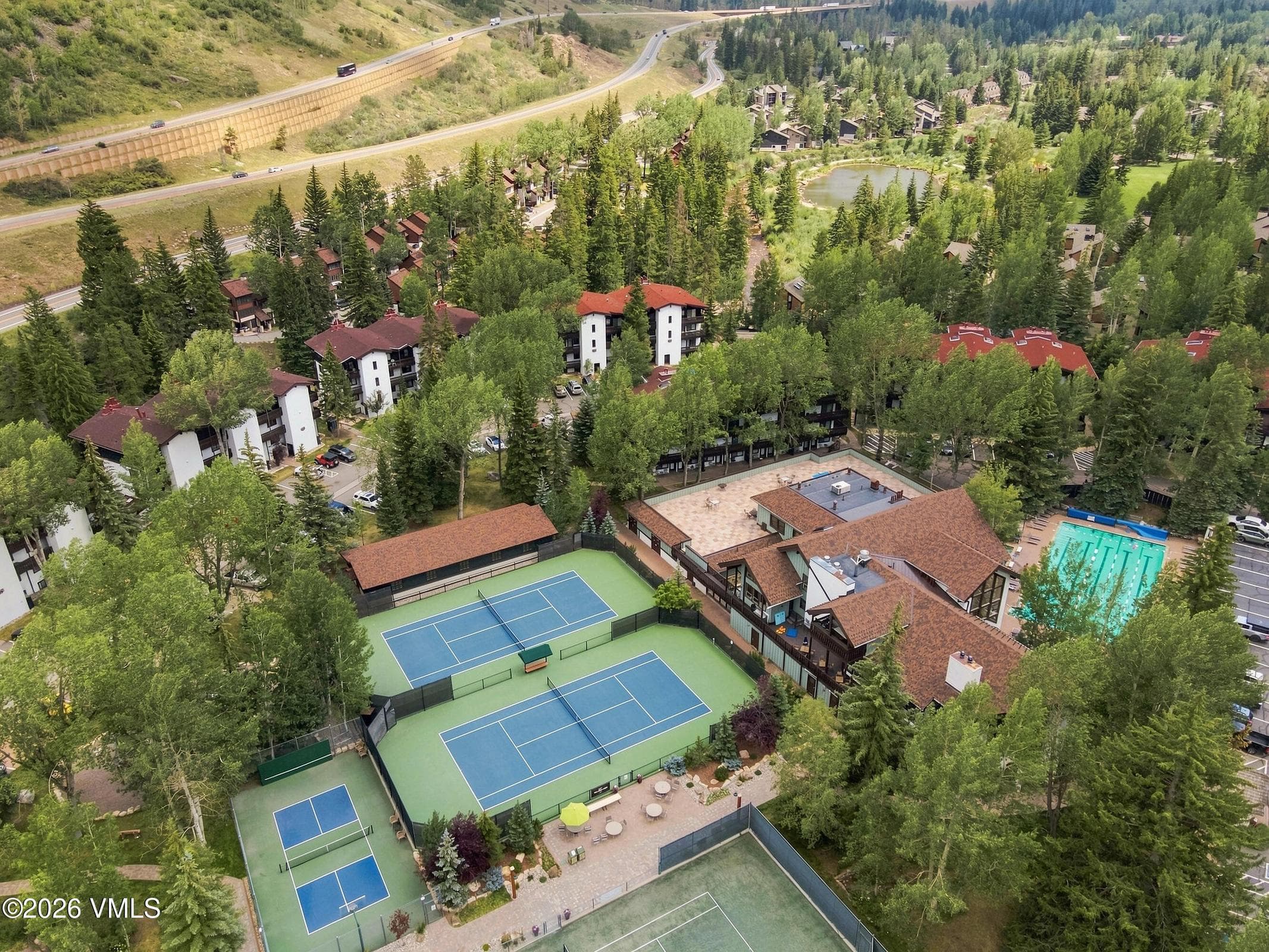 Aerial of the full amenity campus: tennis, pickleball, pool, and pond.